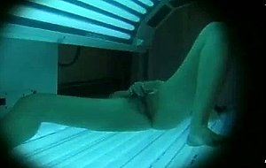 Tanning in a machine while she plays with herself